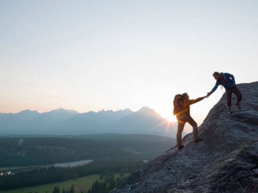 Bergsteiger helfen sich beim Klettern in der Abenddämmerung.