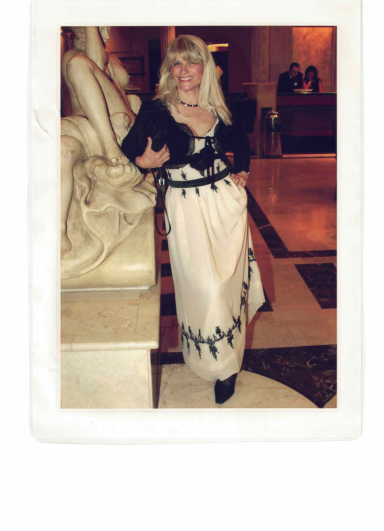 Frau in traditioneller Kleidung mit langen, weißen Rock und schwarzer Bluse, posierend.