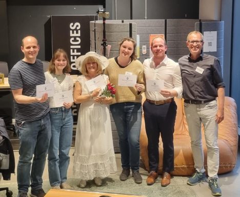 Gruppe von sechs Personen mit Gratulationskarten, eine davon im weißen Kleid mit Blumen.